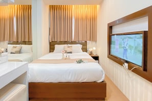Ein Hotelzimmer mit einem großen Bett, Nachttischen, einem Fernseher und Vorhängen.