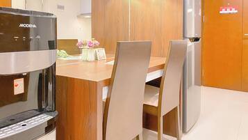 A kitchen with a coffee machine, wooden cabinets, and a refrigerator.