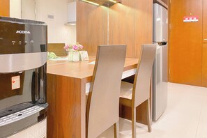 Une cuisine équipée d’une machine à café, de meubles de rangement en bois et d’un réfrigérateur.