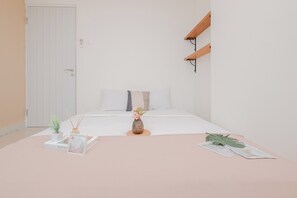 A minimalist bedroom with a bed, a bedside table, a small plant, and a wall-mounted shelf. - 2Br Apartment Near Pakuwon Mall Bekasi At Grand Kamala Lagoon (Bekasi)