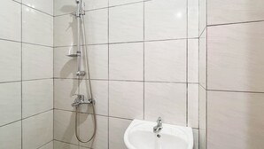 A bathroom with a shower, a sink, and tiled walls. - Restful Living Studio (No Kitchen) At Apartment Bandaraya - Tallasa City Makassar (Makassar)