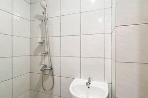 A bathroom with a shower, a sink, and tiled walls. - Restful Living Studio (No Kitchen) At Apartment Bandaraya - Tallasa City Makassar (Makassar)