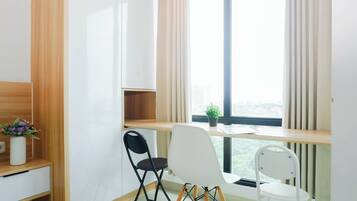 Ein Zimmer mit Schreibtisch, zwei Stühlen, einer Topfpflanze und einem Fenster mit Blick.