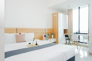 Ein Hotelzimmer mit Bett, Nachttisch, Schreibtisch mit Stuhl, Fenster mit Vorhängen und einem Kleiderschrank.