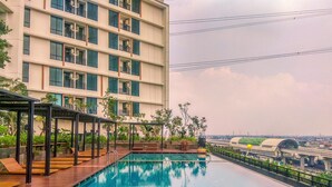 Una piscina sul tetto con vista su un edificio moderno e un ponte sullo sfondo.