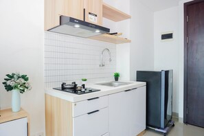Eine kleine Küche mit Gaskochfeld, Spüle und eingebautem Backofen. Auf der Arbeitsfläche steht ein kleiner Blumentopf.