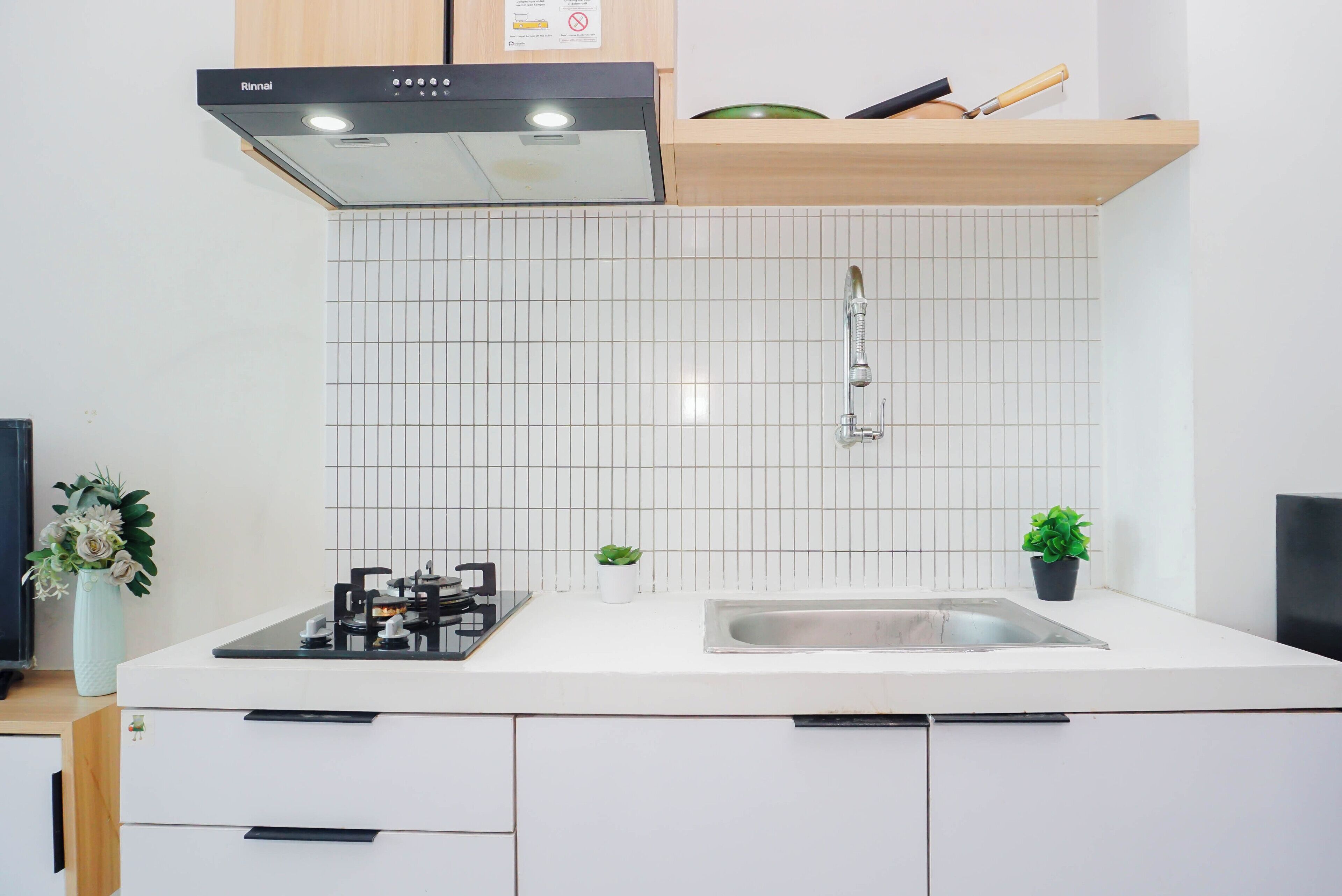 A kitchen with a gas stove, a sink, a range hood, and a tiled backsplash.