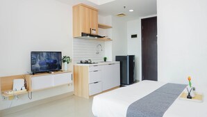 Una camera d'albergo moderna con un letto, una TV, angolo cottura e una porta scura.