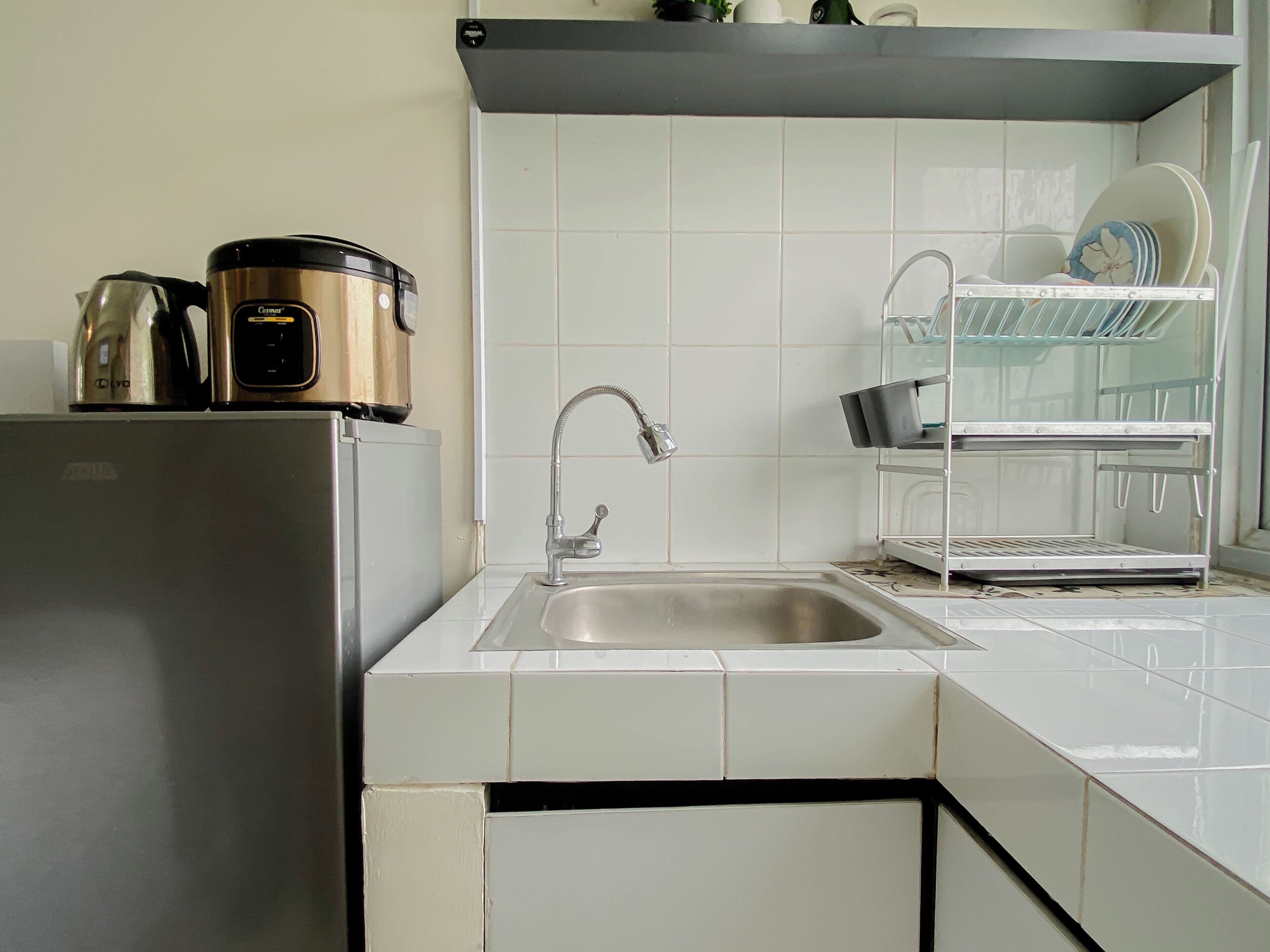 A kitchen with a stainless steel sink, a coffee maker, and a dish rack.