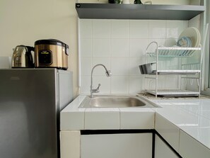 A kitchen with a stainless steel sink, a coffee maker, and a dish rack. - Good Deal Studio Apartment Mont Blanc Bekasi (Bekasi)
