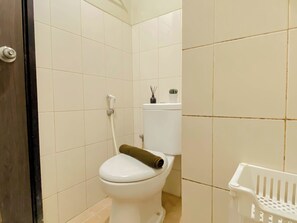 Ein Badezimmer mit Toilette, Dusche und einem weißen Wäschekorb.