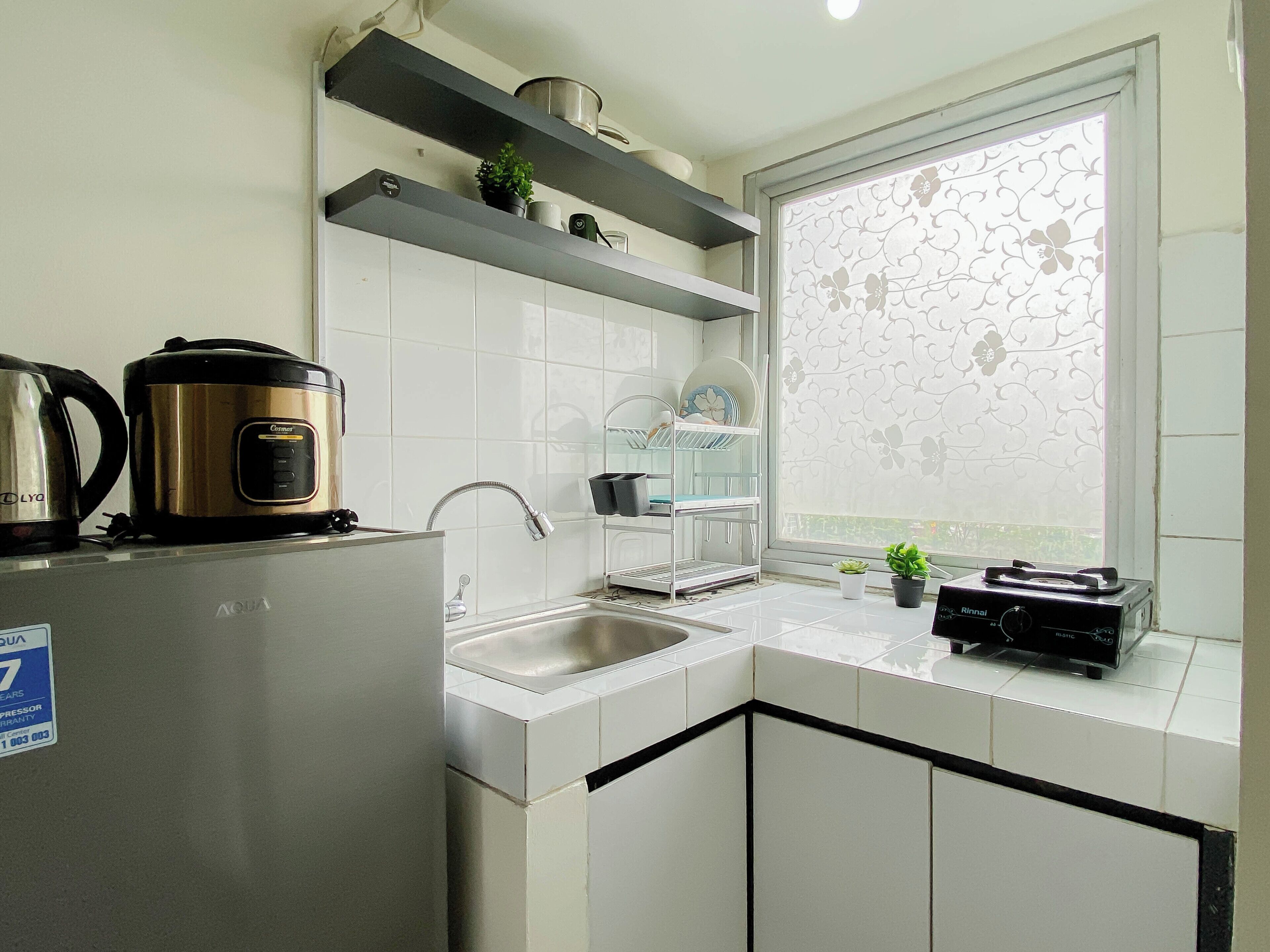 A modern kitchen with white cabinets, stainless steel appliances, and a window with a floral pattern.