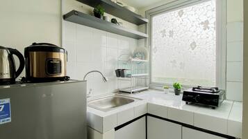 A modern kitchen with white cabinets, stainless steel appliances, and a window with a floral pattern.