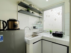 Una cocina moderna con armarios blancos, electrodomésticos de acero inoxidable y un ventanal con estampado floral.
