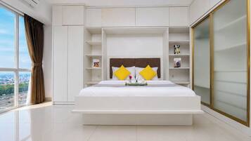 A modern hotel room with a large bed, built-in shelving, and a view of the city.