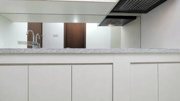 A modern kitchen with a granite countertop, stainless steel faucet, and a black range hood.