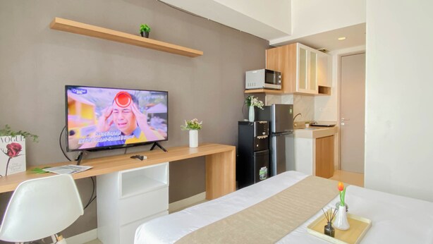 Quarto de hotel moderno com cama, escrivaninha, televisão, micro-ondas e frigorífico.