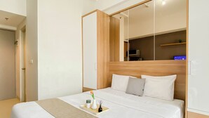 Cama bem arrumada com cabeceira de madeira e mesa de cabeceira com um suporte contendo um vaso e um livro.