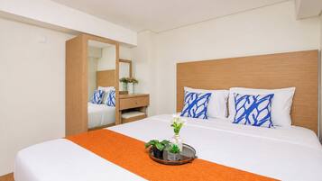 A hotel room with a bed, a nightstand, a dresser, and a mirror.