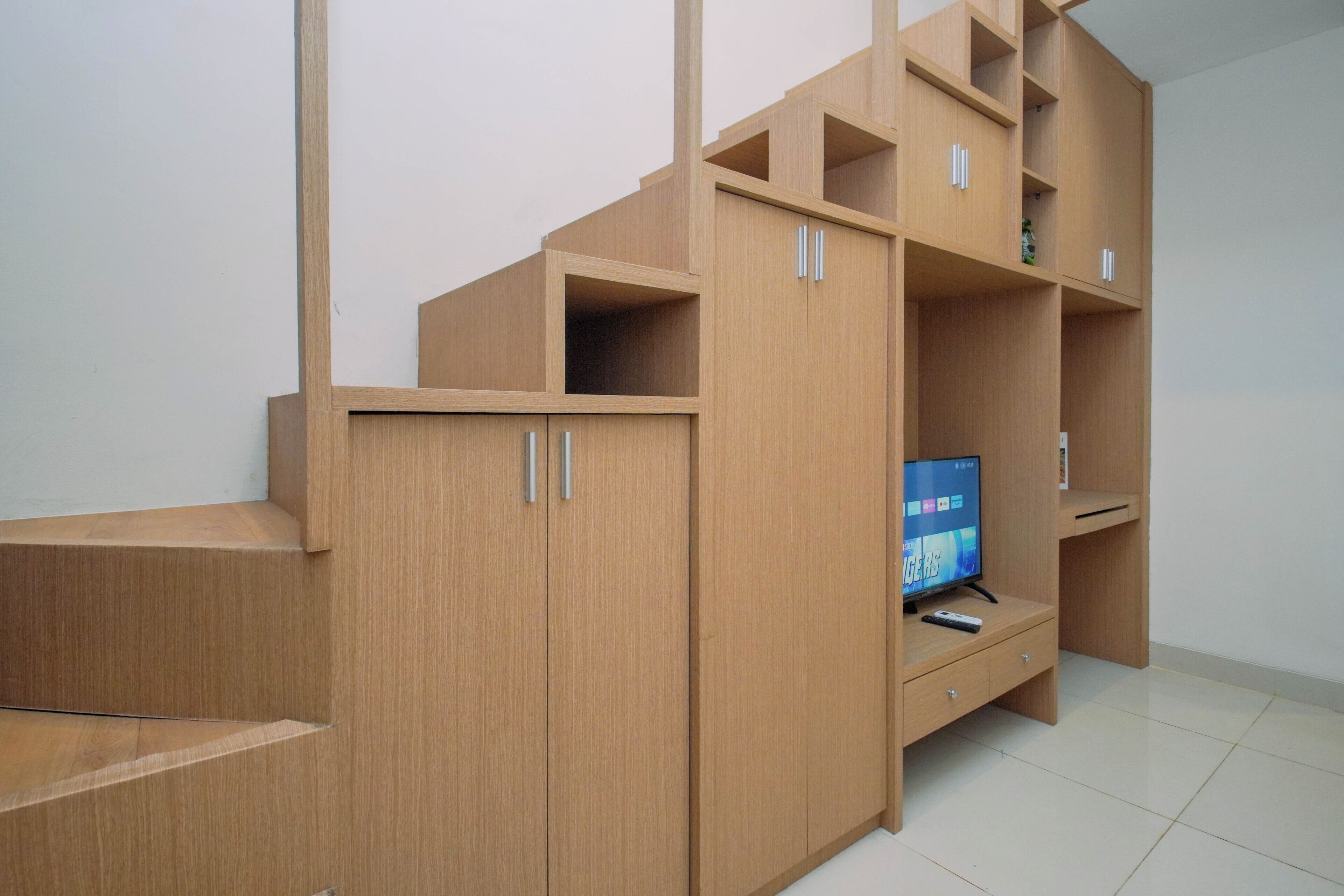 A room with a built-in wooden entertainment unit, a flat-screen TV, and a small cabinet.