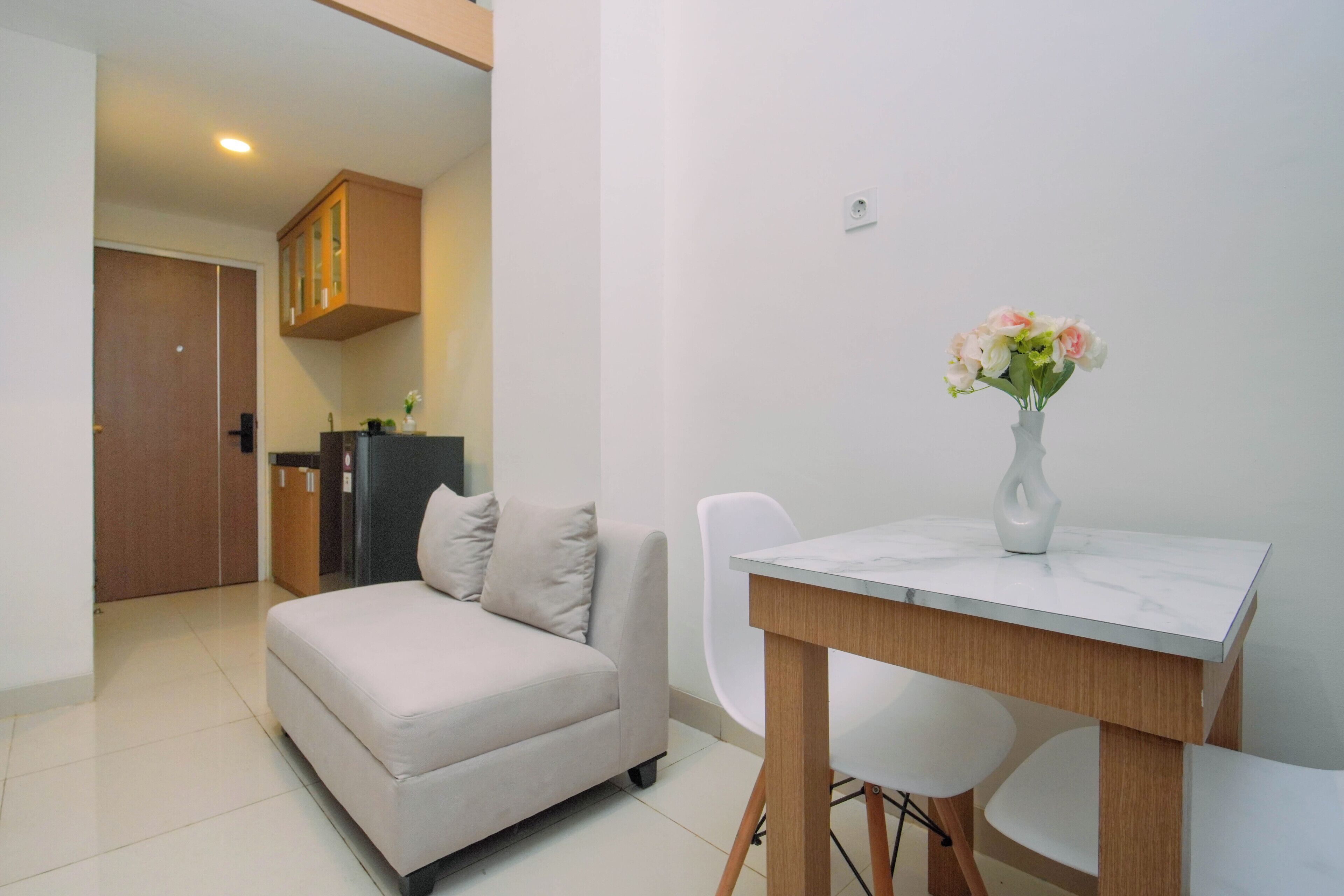 A modern living room with a sofa, a dining table, and a vase of flowers.