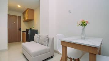 A modern living room with a sofa, a dining table, and a vase of flowers.