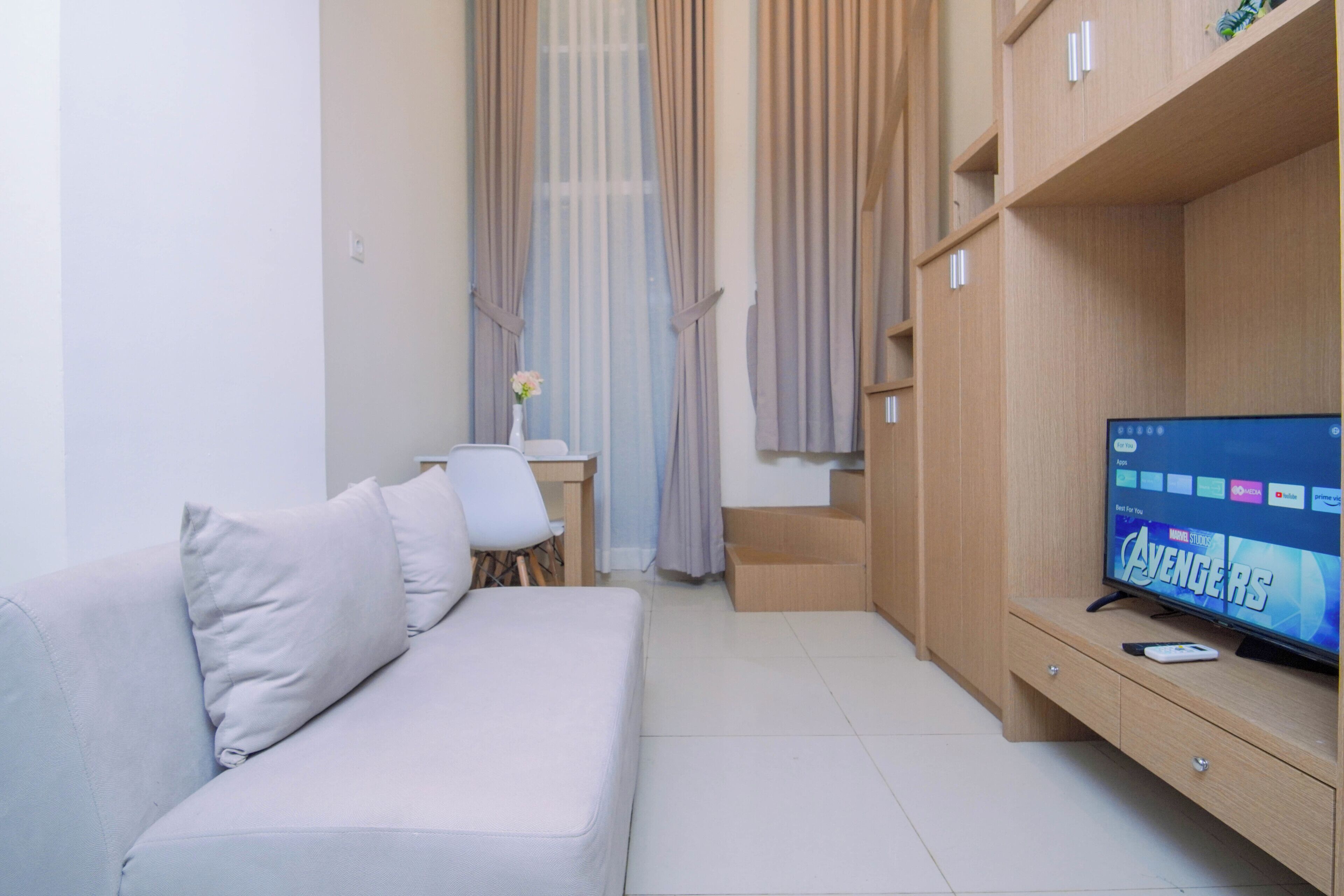 Een moderne woonkamer met een bank, een televisie waarop 'Avengers: Endgame' wordt afgespeeld, en een houten kast.