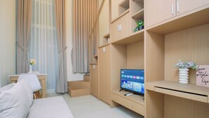 Uma sala de estar moderna com televisão de tela plana, sofá, escrivaninha e estante de livros.