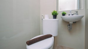 Casa de banho com sanita, lavatório e duas plantas em vasos.