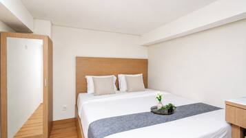 A hotel room with a bed, bedside table, and a mirror.