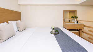 Quarto de hotel com uma cama, mesa de cabeceira com espelho e uma pequena planta na mesa.