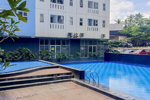 Ein modernes Gebäude mit Swimmingpool, umgeben von Grünflächen und einem Parkplatz.