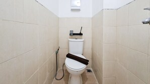A small, narrow bathroom with a toilet, a shower, and a wall-mounted light fixture. - Peaceful And Restful Studio Room At Apartment Urbantown Serpong (Tangerang)