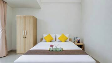 Quarto de hotel com uma cama, guarda-roupa, mesa de cabeceira e uma pequena mesa com bandeja.