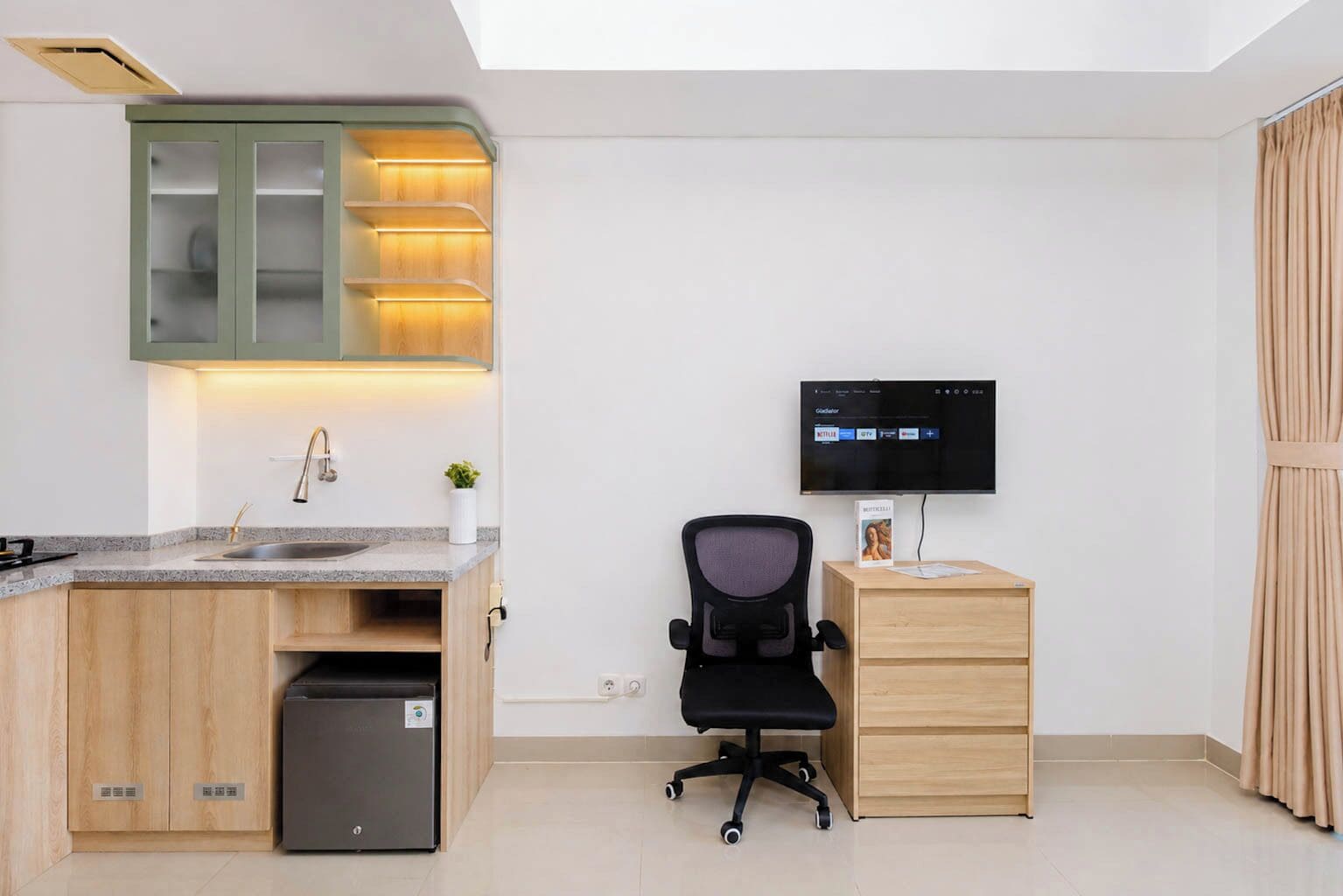 A modern kitchen with a built-in microwave, a sink, and a cabinet with illuminated shelves.