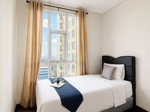 Ein Hotelzimmer mit einem Bett, einem Fenster mit Vorhängen und Blick auf Gebäude.