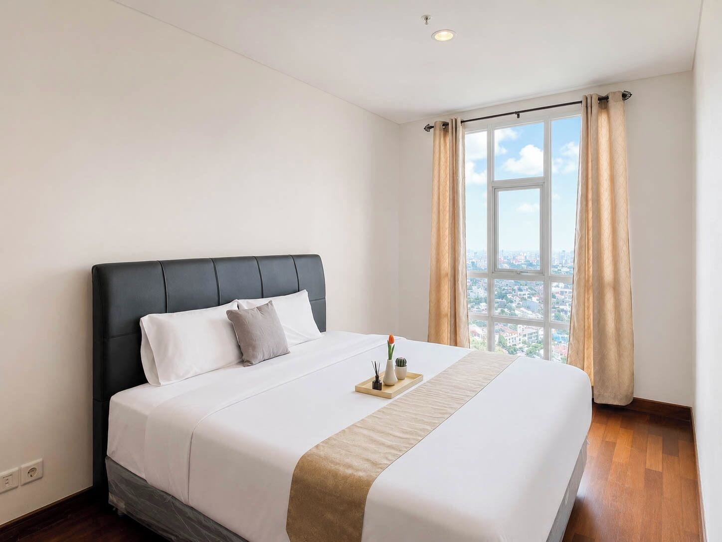 Ein Hotelzimmer mit einem grossen Bett, Blick auf die Stadt durch ein Fenster und Holzboden.