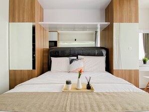 Ein Hotelzimmer mit einem Bett, einem Nachttisch, einer kleinen Topfpflanze und einem Tablett mit einer Vase und einer Kerze.