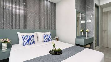 A modern bedroom with a large bed, a bedside table with a vase of flowers, and a wall-mounted mirror.