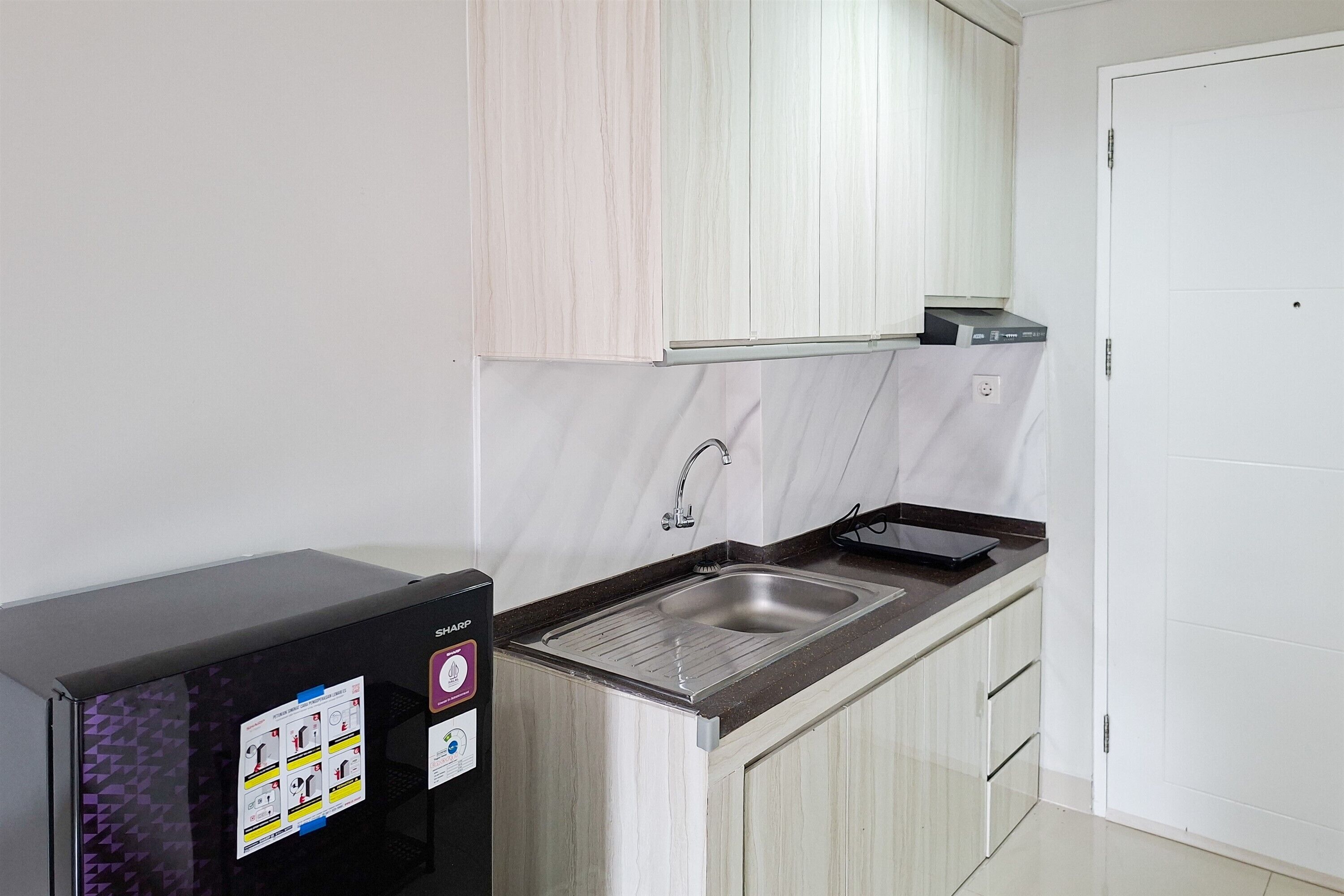 A compact kitchen with a built-in sink, a refrigerator, and a microwave.