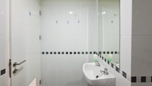Un baño con un lavamanos blanco, un espejo y una pared con azulejos y un borde blanco y negro.