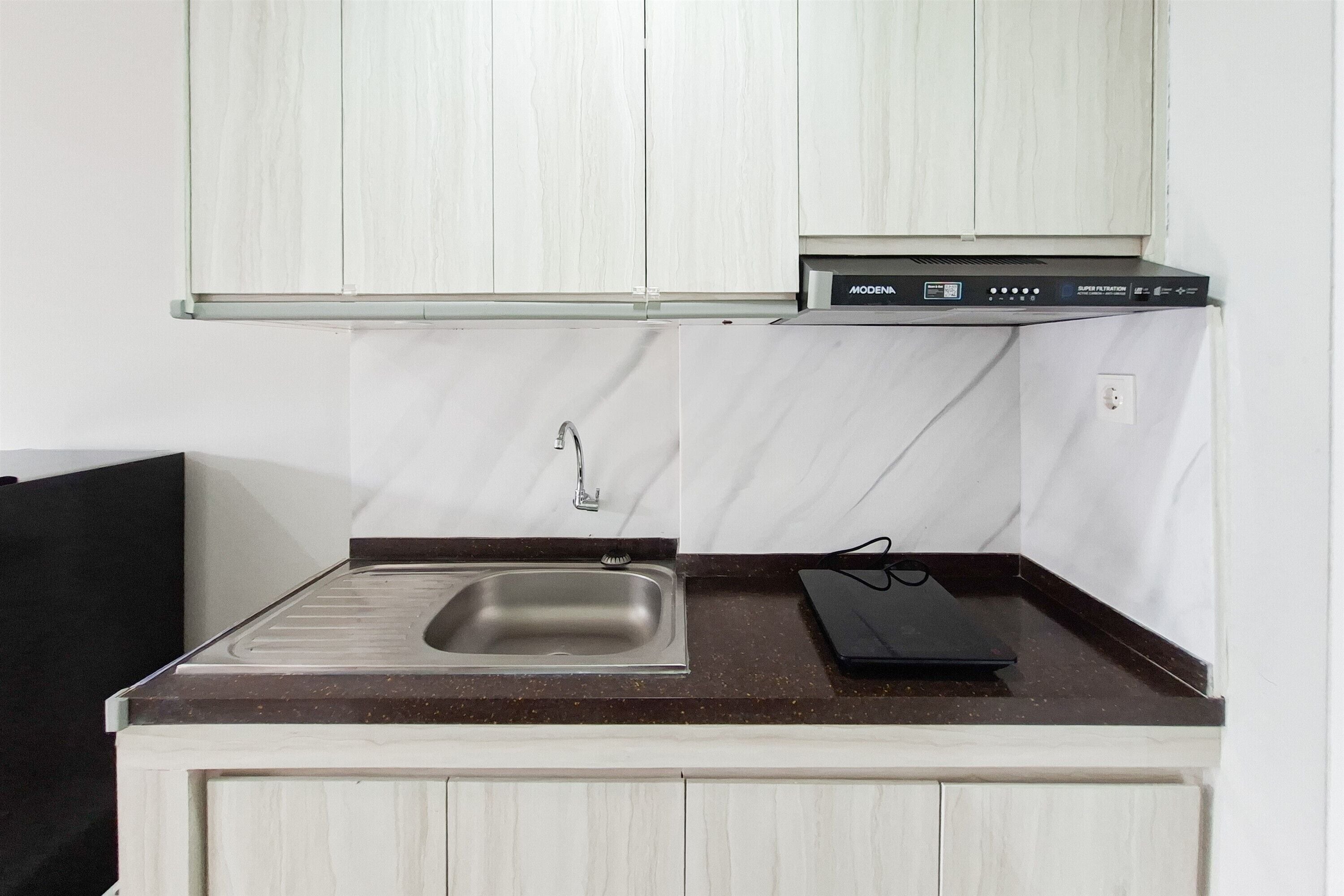 Una cucina compatta con lavello integrato, un forno a microonde e un piccolo piano di lavoro.