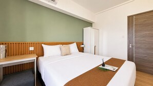 Hotellihuone, jossa on sänky, työpöytä, vaatekaappi ja ovi.