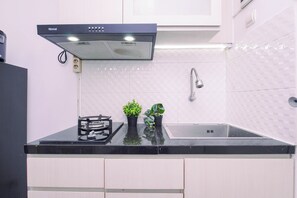 Cozinha moderna com bancada preta, armários brancos, pia de aço inoxidável e coifa preta.