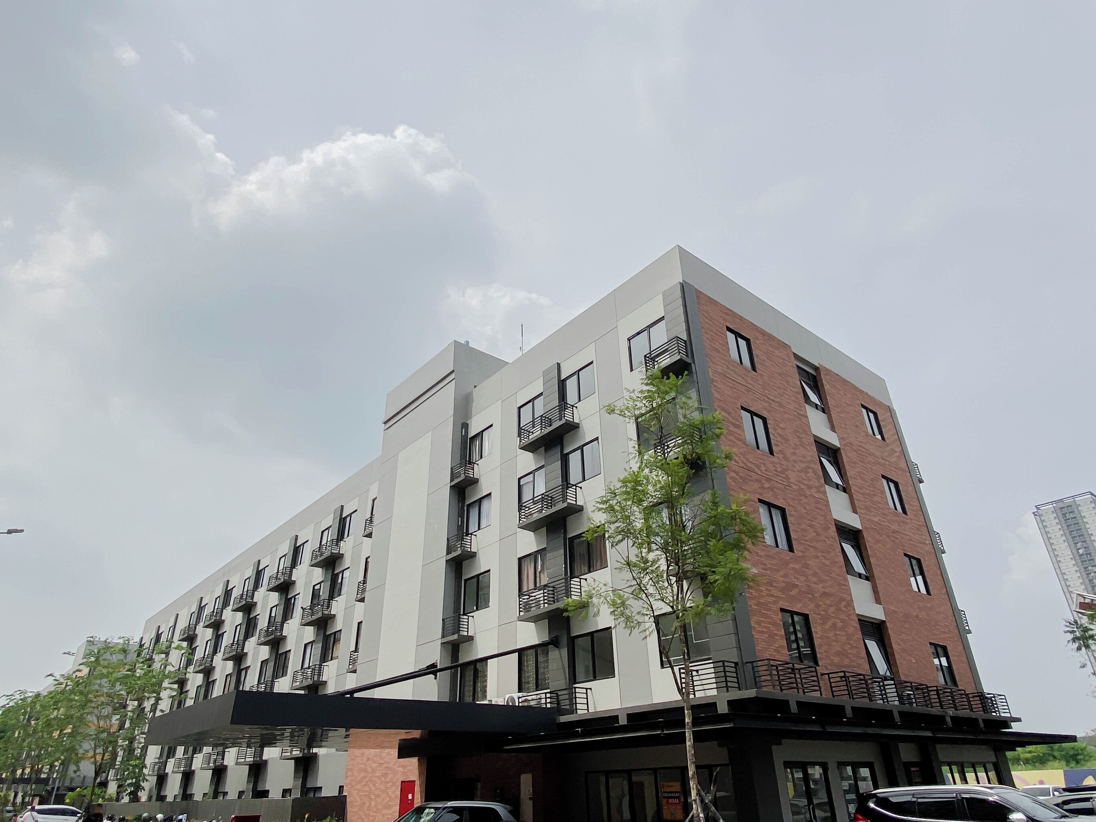 A multi-story building with balconies, a flat roof, and a brick facade.