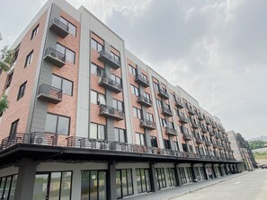 Monikerroksinen rakennus, jossa on parvekkeita, suuret ikkunat ja katettu sisäänkäyntialue.