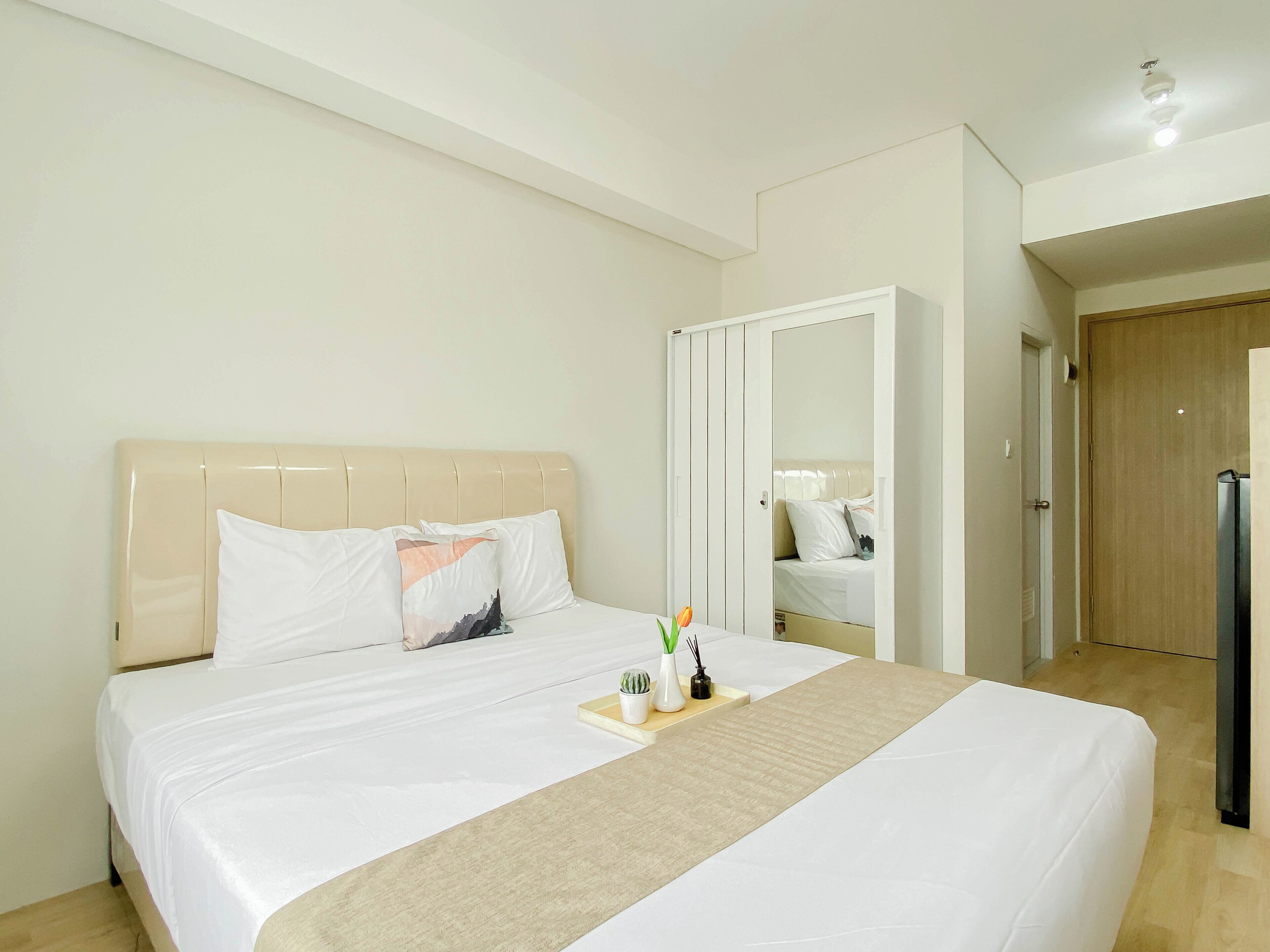 A hotel room with a bed, a bedside table, a mirror, and a wardrobe.