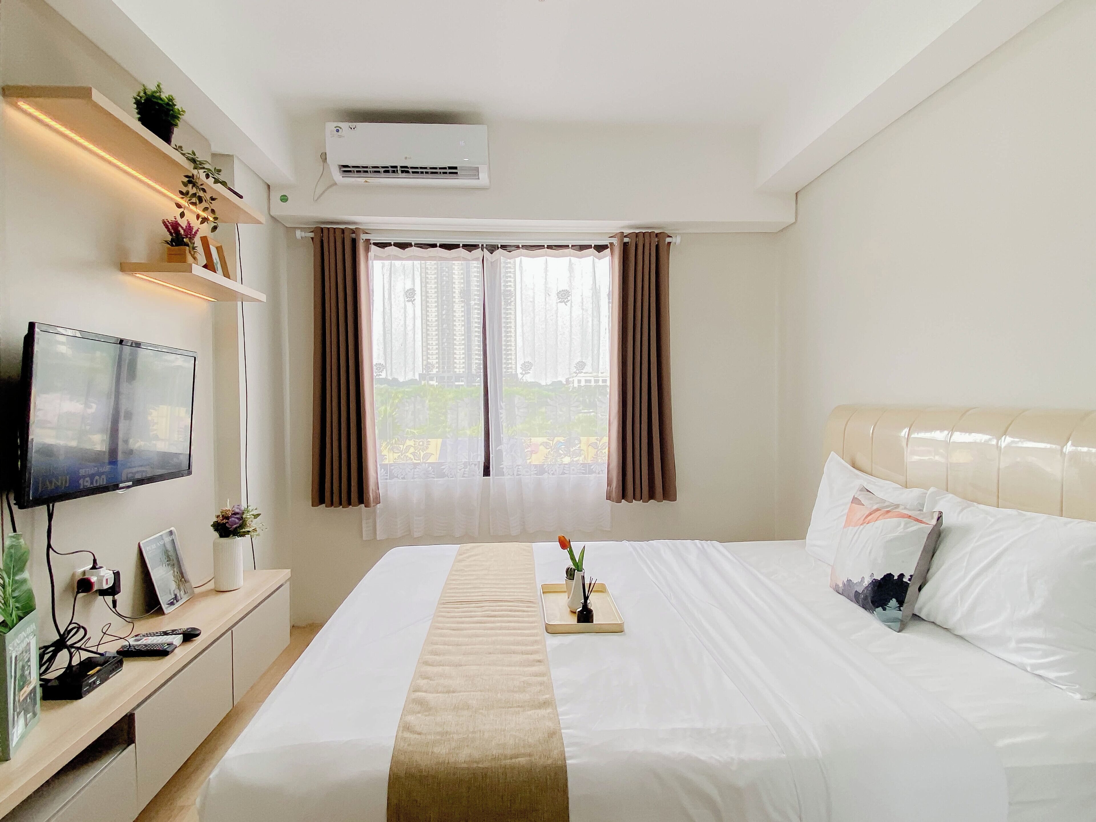 Una habitación de hotel con cama, televisión, escritorio y ventana con cortinas.