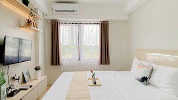 Una habitación de hotel con cama, televisión, escritorio y ventana con cortinas.