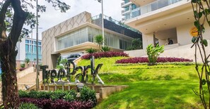 A modern building with a prominent entrance sign, a well-maintained lawn, and a staircase leading to the entrance. - Comfortable And Homey 1Br At Apartment Tree Park City Bsd (Tangerang)